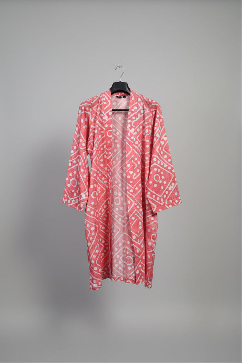 Pink patterned garment hanging against a wooden fence with greenery